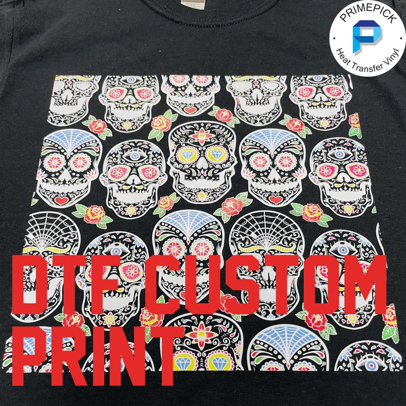 May include: Black t-shirt with a white and colorful sugar skull pattern. The text "DTG CUSTOM PRINT" is printed in red on the front of the shirt.