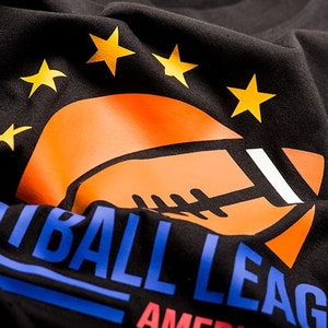 May include: Black t-shirt with a blue and orange graphic of a football and the text "Football League America" with five yellow stars above the football.