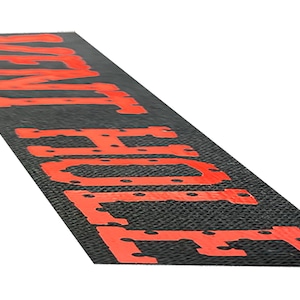 May include: Black and red floor mat with the words "VENT HOLE" printed in red.