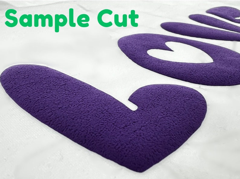 May include: A close-up of a purple felt "Love" cutout with a heart shape in the center. The text "Sample Cut" is visible in the top left corner of the image.