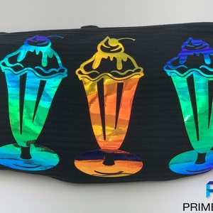 Pu&ograve; includere: Tre disegni di milkshake arcobaleno iridescenti su uno sfondo di tessuto nero. I milkshake hanno una ciliegia in cima e un vortice che cola.