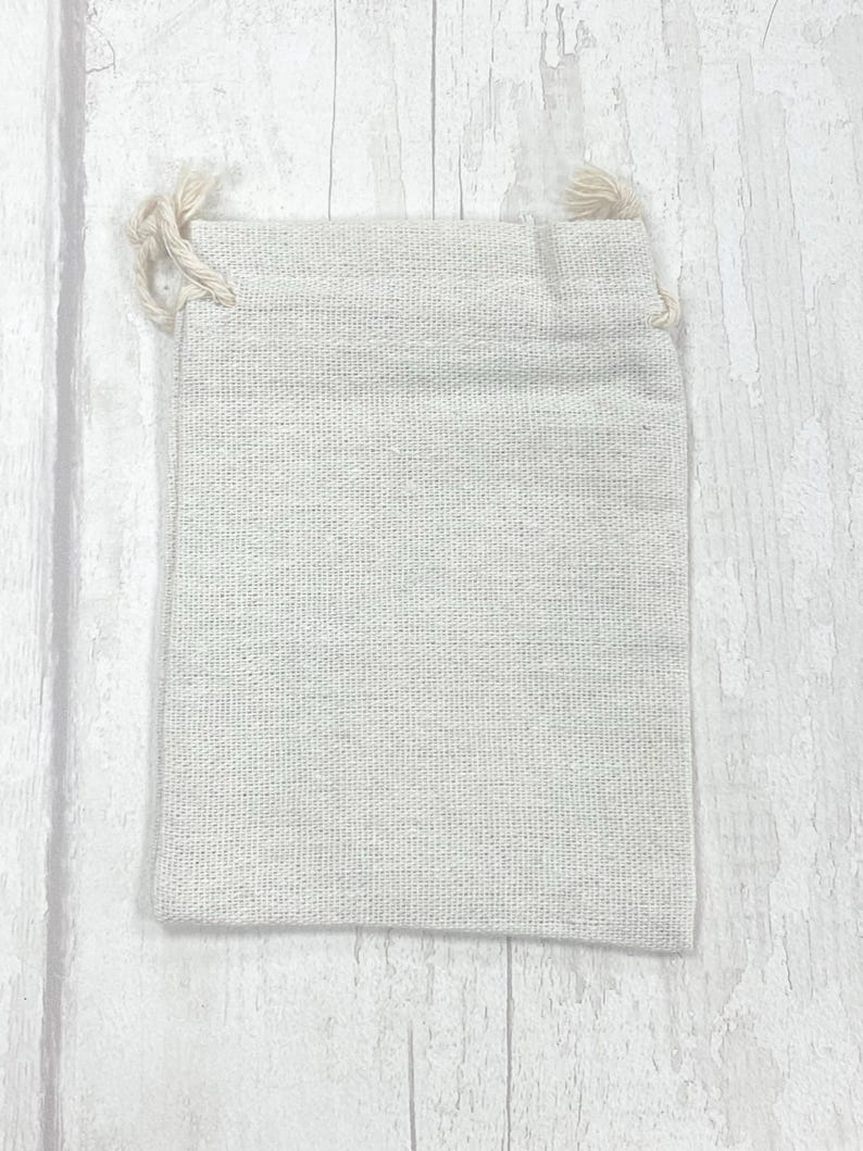 May include: A small, off-white, drawstring pouch made of natural fabric. The pouch is empty and has a simple, rustic look.