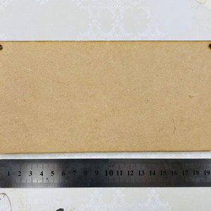 May include: A plain, rectangular, brown wooden sign with two holes for hanging. The sign is approximately 20 inches long and 6 inches wide.