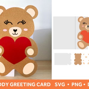 May include: A brown teddy bear holding a red heart. The bear has a brown nose, black eyes, and pink cheeks. The heart is outlined in black. The image is for a greeting card.