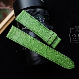 May include: Two green alligator watch straps with white stitching. The straps are made of genuine leather and are handmade. The brand name "I-STIZ LEATHER HANDMADE" is visible in the image.