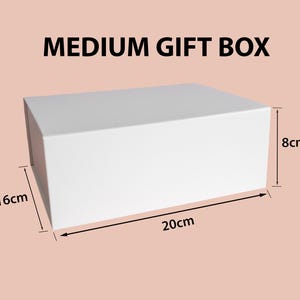 Może przedstawiać: Prostokątne białe pudełko prezentowe z napisem MEDIUM GIFT BOX. Pudełko posiada nadrukowane wymiary 20 cm długości, 16 cm szerokości i 8 cm wysokości, co zapewnia wyraźną wizualną reprezentację fizycznego rozmiaru tego pojemnika do przechowywania.