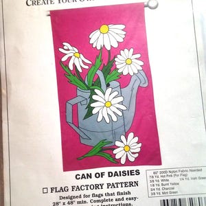 May include: A sewing pattern for a flag featuring a white watering can with daisies on a pink background. The pattern is called "Can of Daisies" and is from the Flag Factory. The pattern is designed for flags that finish at 28 inches by 48 inches. The pattern includes instructions for sewing the flag.