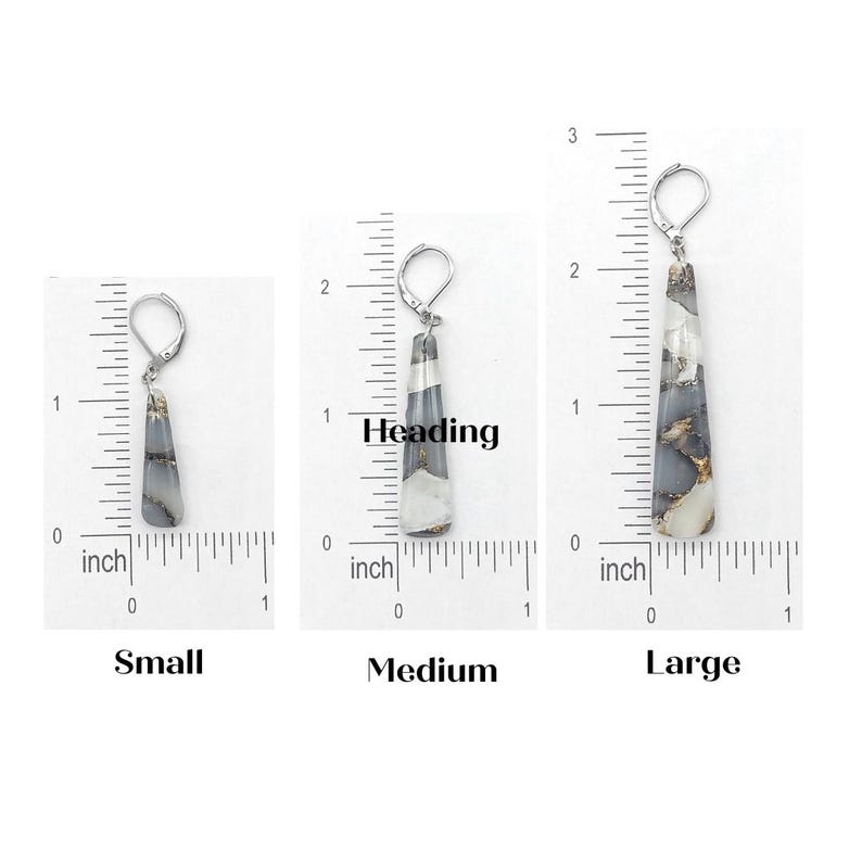 May include: Three pairs of silver dangle earrings with a long, teardrop-shaped stone. The stones are a white and gray color with black and gold flecks. The earrings are shown next to a ruler, with the smallest measuring 1 inch, the medium measuring 1.5 inches, and the largest measuring 2 inches.