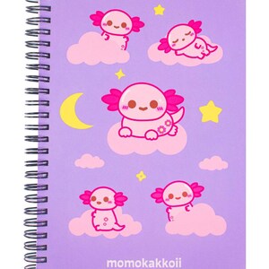 May include: A spiral-bound notebook with a lavender cover featuring a repeating pattern of pink axolotls, clouds, stars, and a crescent moon. The text "momokakkoii" is printed at the bottom.