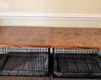 May include: Two black metal dog crates with gray bedding inside, sitting on top of a wooden bench.