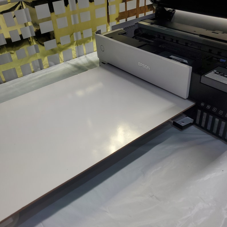 May include: A white printer with the word "EPSON" printed on the front. A white rectangular piece of paper is being fed into the printer.