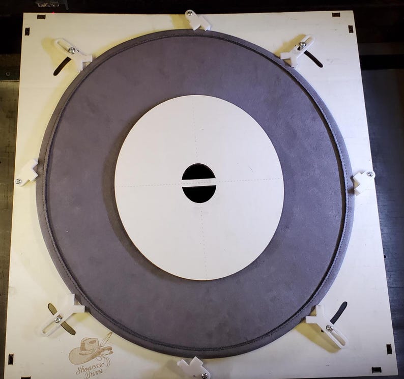 May include: A circular drum head with a gray outer ring and a white inner circle. The center has a black horizontal oval. The drum head is secured to a wooden frame with white clips. The text "Showcase Drums" is visible in the lower left corner.
