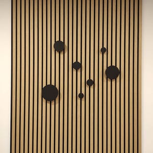 Puede incluir: Un panel de pared de madera con vetas verticales y rayas negras. Varios acentos circulares negros est&aacute;n dispuestos en el panel. El panel es un elemento decorativo para el dise&ntilde;o de interiores.