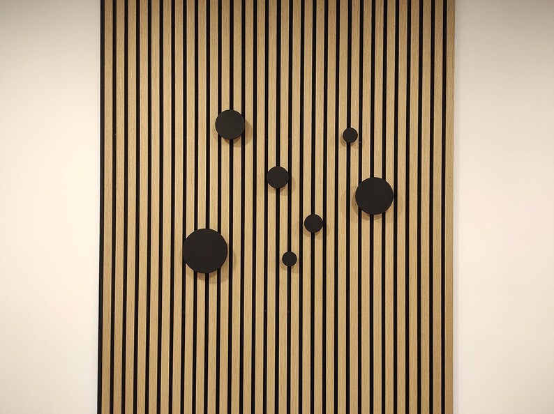 Puede incluir: Un panel de pared de madera con vetas verticales y rayas negras. Varios acentos circulares negros est&aacute;n dispuestos en el panel. El panel es un elemento decorativo para el dise&ntilde;o de interiores.