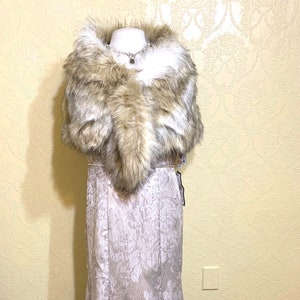 May include: A long, flowing, silver-grey formal gown with a floral pattern. The gown is paired with a brown and white faux fur shawl.