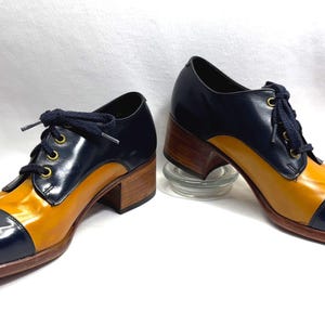 May include: A pair of blue and yellow heeled shoes with a lace-up closure. The shoes have a rounded toe and a chunky heel.