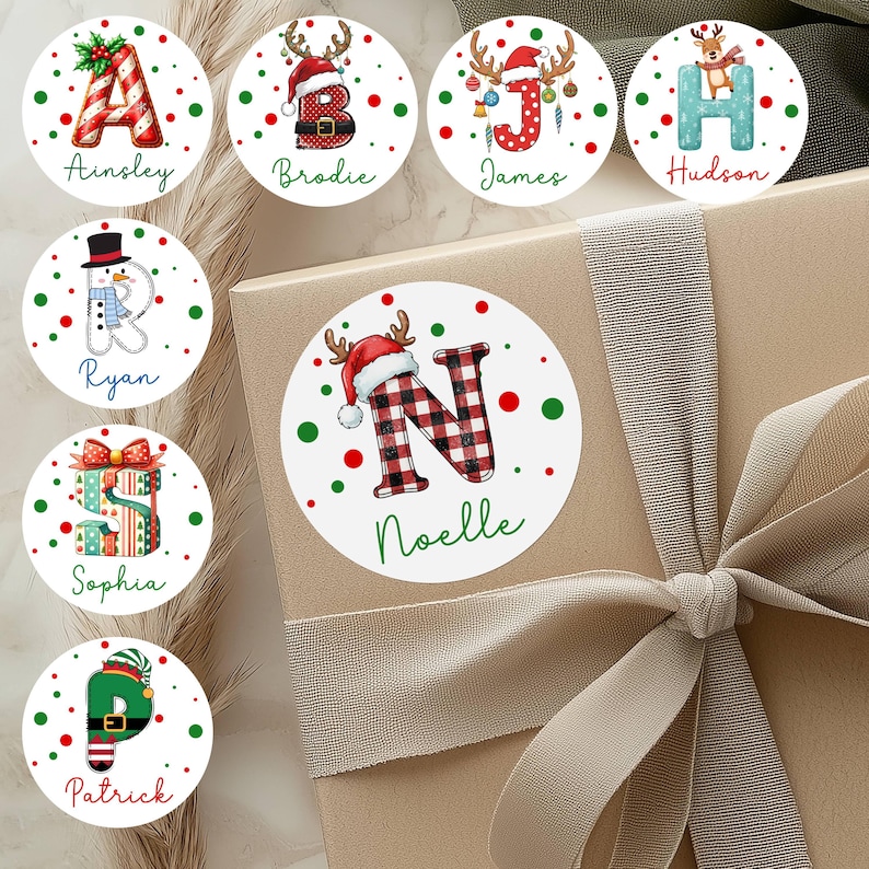 May include: A collection of personalized Christmas gift stickers. Each sticker features a letter of the alphabet, a name, and festive holiday designs like reindeer antlers, Santa hats, and Christmas presents. The stickers are round with red and green accents.