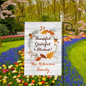 Może przedstawiać: Biały drewniany znak z jesiennym wieńcem z liści, żołędzi i jag&oacute;d. Na znaku widnieje napis "Thankful Grateful & Blessed!" i "The Robinson Family".