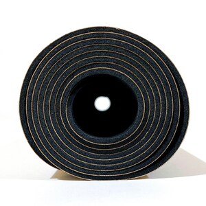 May include: A tightly rolled black foam mat viewed from the end, revealing a circular cross-section with concentric rings. The material has a porous, textured appearance with thin, light-colored lines separating each layer of the rolled foam.