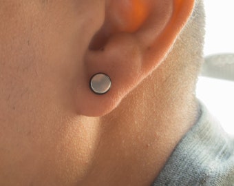 May include: A person with a silver ear gauge in their right earlobe.