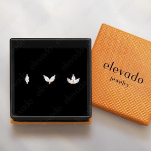 May include: A white ceramic mug with a black handle and the text "But First, Coffee" in a bold, black font. The mug is set against a blurred background, highlighting its clean design.