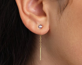 Könnte beinhalten: Ein Paar goldene Ohrringe mit einem kleinen violetten Edelstein und einer baumelnden Kette.