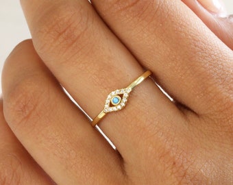 May include: A gold ring with a turquoise evil eye charm and clear cubic zirconia stones.