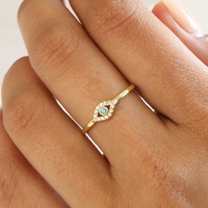 May include: A gold ring with a turquoise evil eye charm and clear cubic zirconia stones.