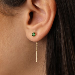 May include: A pair of gold earrings with a small green gemstone and a dangling chain.