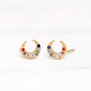 May include: A pair of gold crescent moon earrings with colorful gemstones. The earrings are small and delicate, and they would make a great gift for someone who loves celestial jewelry.