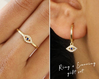 May include: Gold ring and hoop earring set with a blue evil eye charm. The ring and earring are both adorned with clear cubic zirconia stones.
