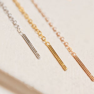Puede incluir: Tres cadenas delicadas con puntas de metal de diferentes colores. Las cadenas son plateadas, doradas y de oro rosa.