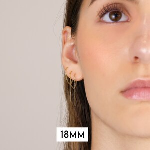 Puede incluir: Primer plano de la oreja de una persona con un pendiente de cadena dorada con tres cadenas colgantes. El pendiente mide 18 mm de largo.