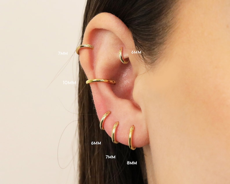 May include: Close-up of a person's ear with multiple gold hoop earrings in different sizes: 6mm, 7mm, 8mm, and 10mm.