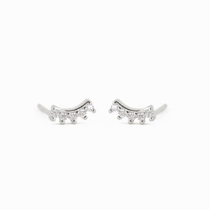 May include: A pair of silver earrings with a curved design and small clear stones.