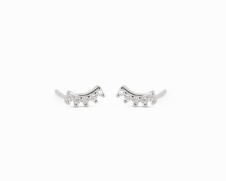 May include: A pair of silver earrings with a curved design and small clear stones.
