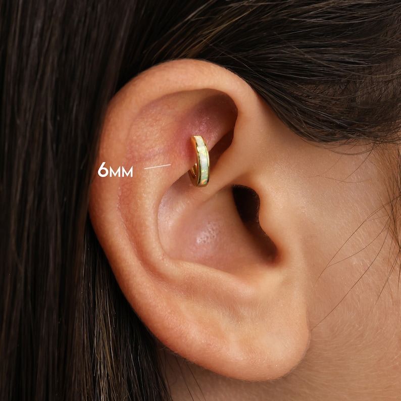 May include: A gold hoop earring with a white opal inlay. The hoop is 6mm in diameter.