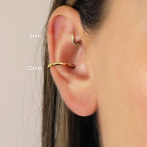 May include: Close-up of a person's ear with two gold hoop earrings. The smaller hoop is 6mm in diameter and the larger hoop is 10mm in diameter.