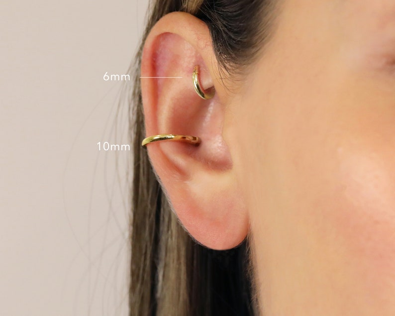 May include: Close-up of a person's ear with two gold hoop earrings. The smaller hoop is 6mm in diameter and the larger hoop is 10mm in diameter.