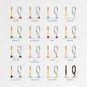K&ouml;nnte beinhalten: Ein Set mit 14 Paaren silberner Creolen mit einem baumelnden Edelstein-Anh&auml;nger. Die Edelsteine sind in verschiedenen Farben, darunter Rot, Gr&uuml;n, Blau, Lila, Pink, Gelb und Schwarz.