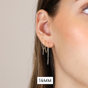Puede incluir: Pendientes de cadena de oro con una longitud de ca&iacute;da de 14 mm. Los pendientes se muestran en la oreja de una modelo.
