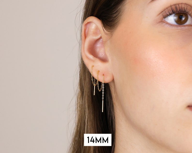 Puede incluir: Pendientes de cadena de oro con una longitud de ca&iacute;da de 14 mm. Los pendientes se muestran en la oreja de una modelo.