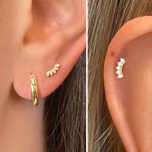 Op de afbeelding: Twee close-ups van een oor met gouden oorringen. De linker afbeelding toont een gouden oorring en een kleine gouden oorring met een rij kleine, heldere stenen. De rechter afbeelding toont een gouden oorring met een gebogen rij kleine, heldere stenen.