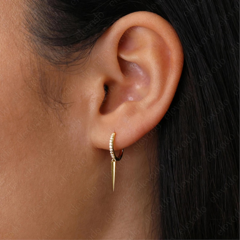 May include: A gold hoop earring with a small diamond-encrusted band and a sharp, pointed drop pendant.