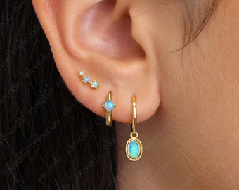 Può includere: Orecchini a cerchio in oro con una pietra preziosa di opale pendente. Gli orecchini a cerchio sono semplici ed eleganti, mentre la pietra preziosa di opale pendente aggiunge un tocco di brillantezza e colore. Gli orecchini sono perfetti per l'uso quotidiano o per un'occasione speciale.