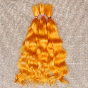 May include: Three bundles of bright orange wavy hair extensions, each secured with a different colored hair tie: red, pink, and black. The hair has a vibrant, sunny hue and a natural-looking wave pattern.