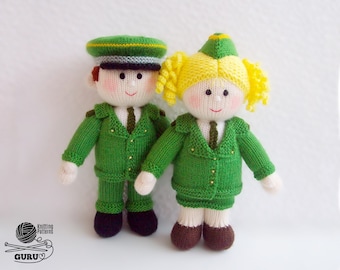 Può includere: Due bambole di lana che indossano uniformi verdi con bottoni dorati e cappelli. La bambola femminile ha i capelli biondi e la bambola maschile ha i capelli castani.