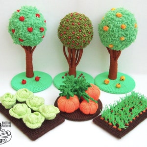 May include: Crocheted miniature garden set with three trees, a patch of carrots, a patch of pumpkins, and a patch of cabbage. The trees are an apple tree, a cherry tree, and an orange tree. The trees are all green with brown trunks. The patches are all green with brown soil.