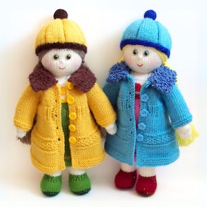 May include: Two knitted dolls wearing winter clothing. The doll on the left is wearing a yellow coat with brown trim and a brown hat. The doll on the right is wearing a blue coat with a blue hat.