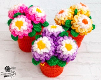 Può includere: Arrangiamenti floreali fatti a mano all'uncinetto in piccoli vasi arancioni. I fiori sono in tonalità di rosa, viola, giallo e bianco, con foglie verdi e centri gialli. L'immagine presenta diversi arrangiamenti.